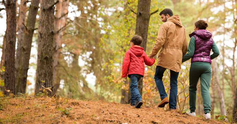 Mutter und Vater spazieren durch einen Herbstwald